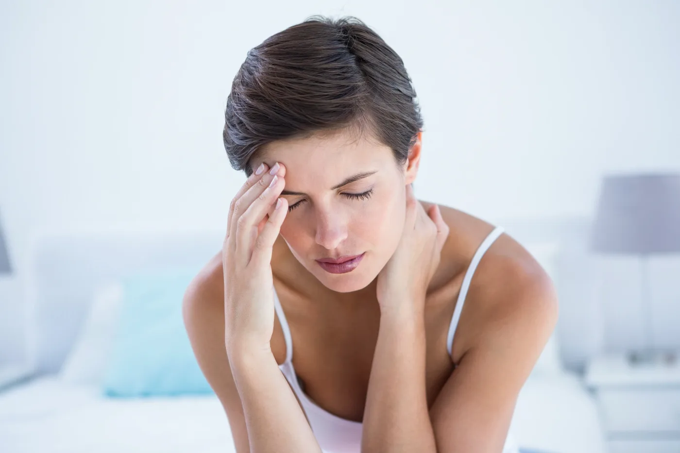 woman holding her temple and neck in pain at home