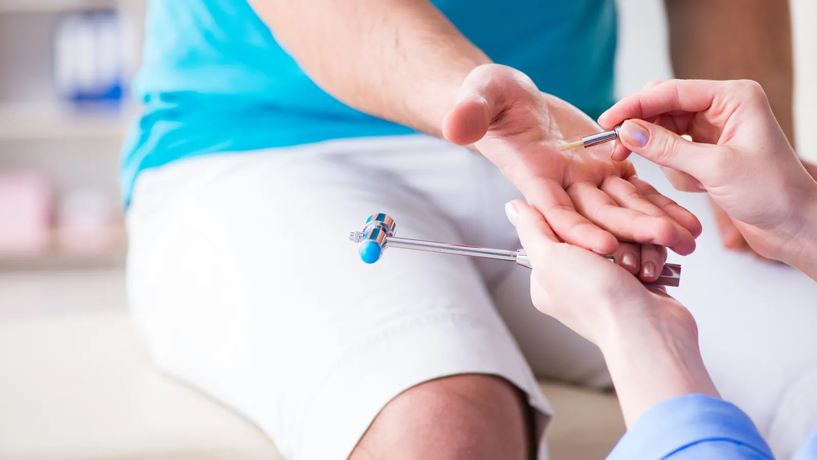 Clinician checking a patient's hand reflexes with a reflex hammer